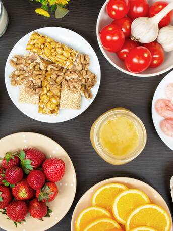 Various foods such as strawberries, shrimps, nuts, tomatoes, eggs and honey on plates