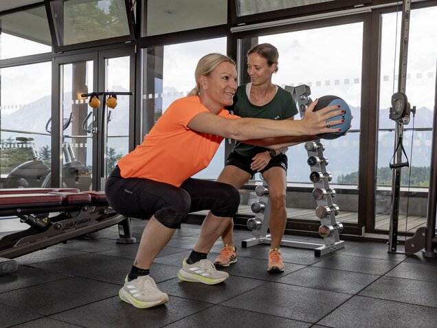 Maria Höfl-Riesch doing strength training in the bright fitness room with views of the Tyrolean mountains