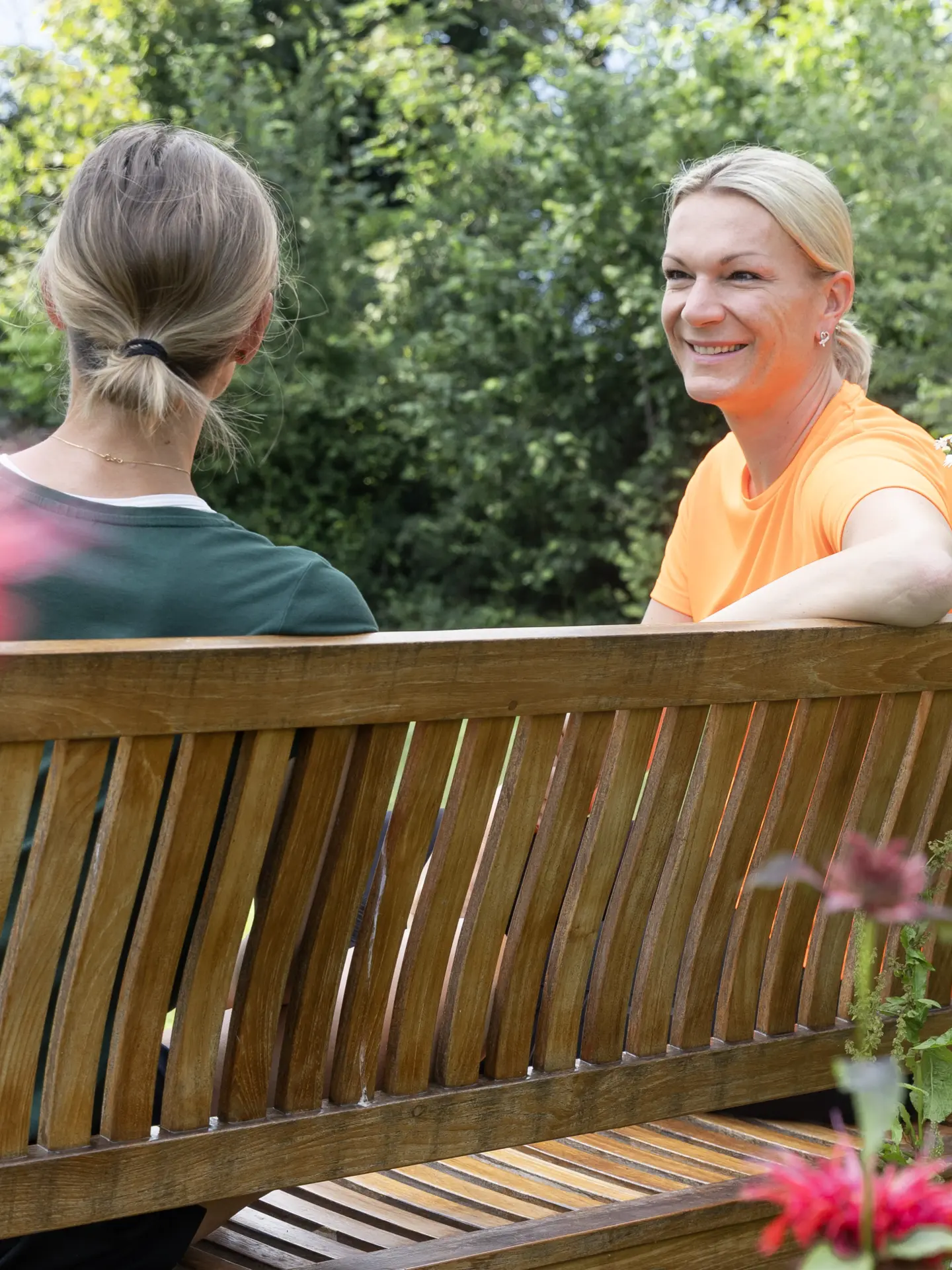 Maria Höfl-Riesch talking with a female guest on a park bench in the garden at Park Igls