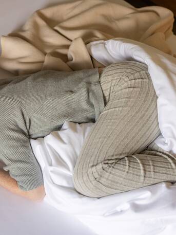 Woman in loungewear curled up in bed – rest and retreat during menstrual discomfort