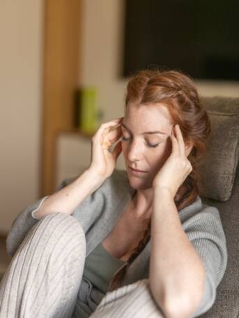 Nachdenkliche Frau mit langen roten Haaren – Moment der Selbstreflexion im Park Igls Medical Spa Resort