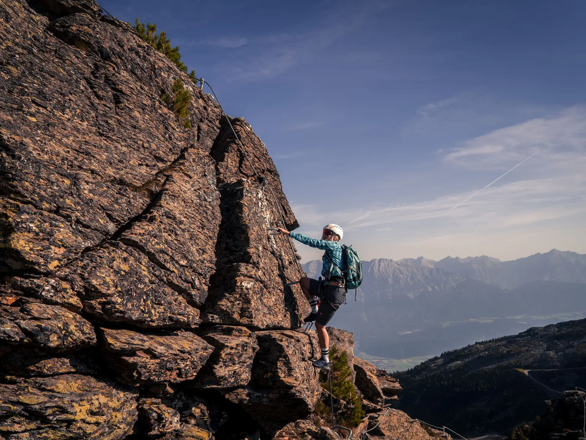 Kletterer am Fels mit Klettersteig-Sicherung, Bergpanorama im Hintergrund | © Tourismusverband Hall-Wattens