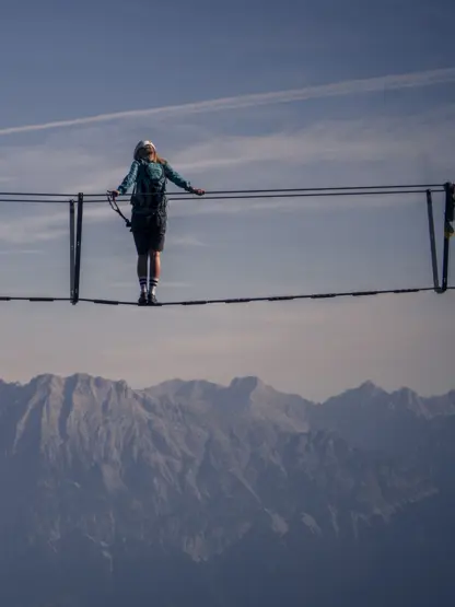 Person auf Hängebrücke vor Bergpanorama am Glungezer Klettersteig