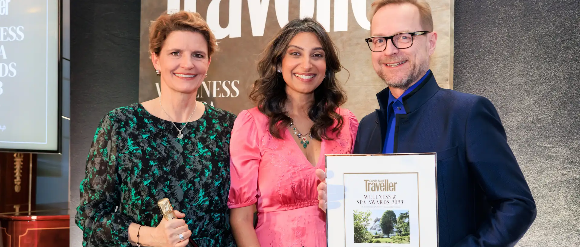Three people proudly present an award in front of a Condé Nast Traveller banner