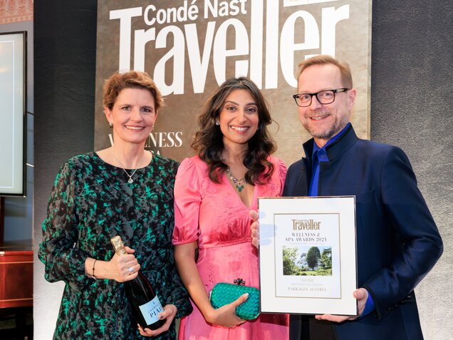 Three people proudly present an award in front of a Condé Nast Traveller banner