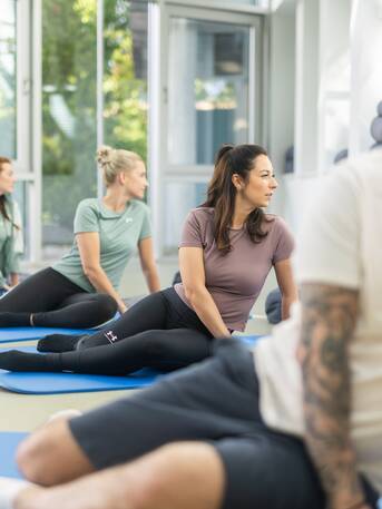 Gruppe von Menschen bei Feldenkrais-Übungen am Boden unter Anleitung eines Therapeuten