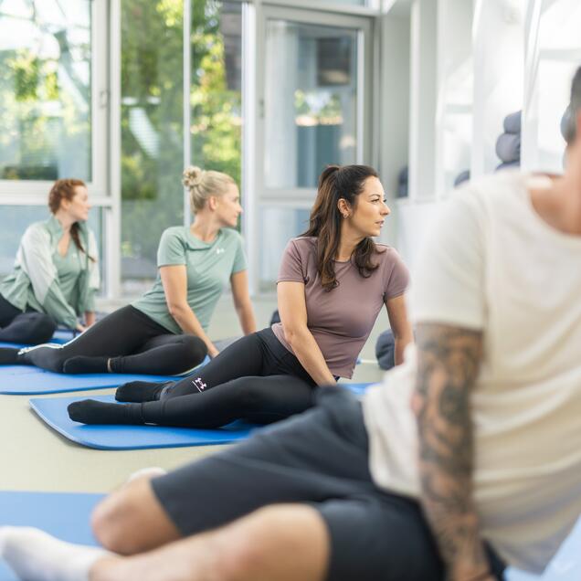 Gruppe von Menschen bei Feldenkrais-Übungen am Boden unter Anleitung eines Therapeuten