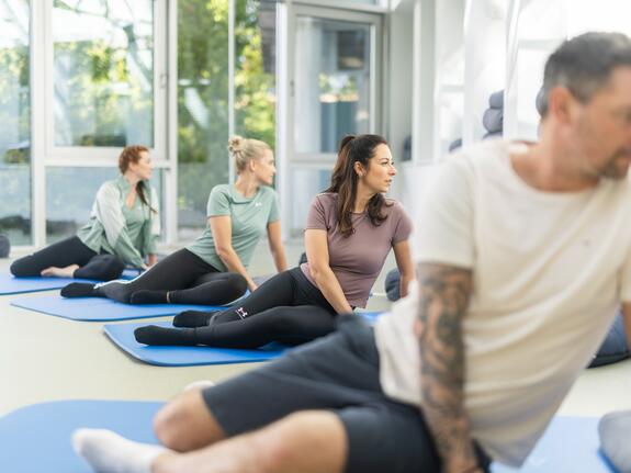 Gruppe von Menschen bei Feldenkrais-Übungen am Boden unter Anleitung eines Therapeuten