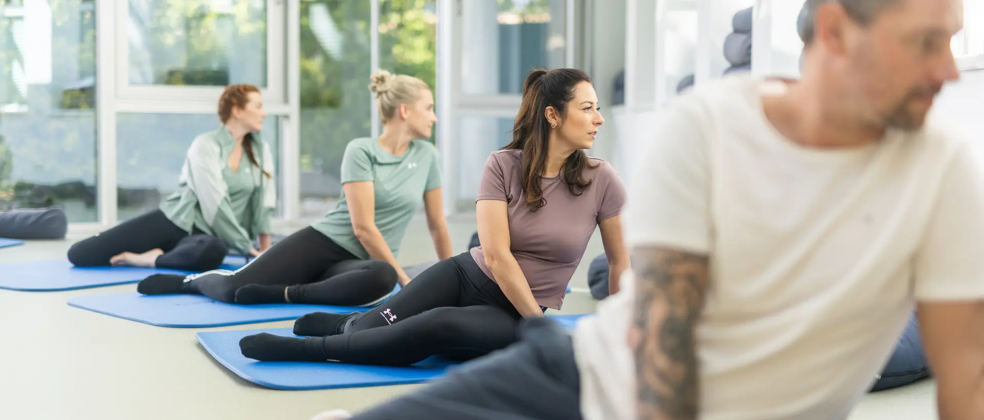 Group of people practicing Feldenkrais exercises on the floor guided by a therapist