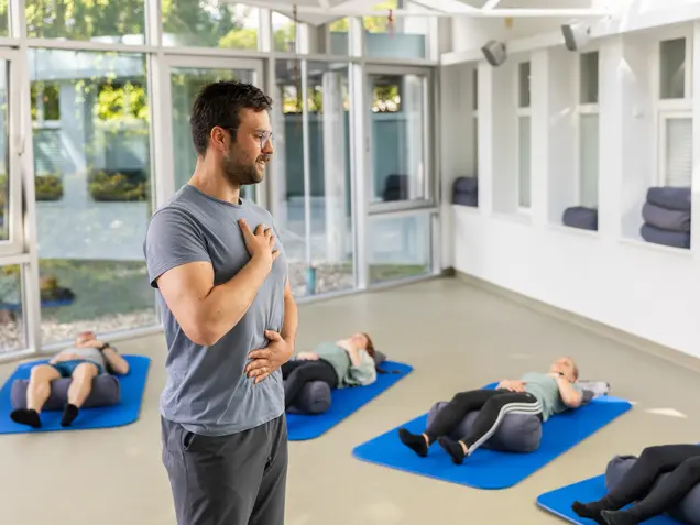 Group of people practicing Feldenkrais exercises on the floor guided by a therapist