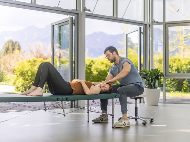 Feldenkrais Therapeut gibt einer Patientin einfühlsam Anleitung bei einer Körperübung