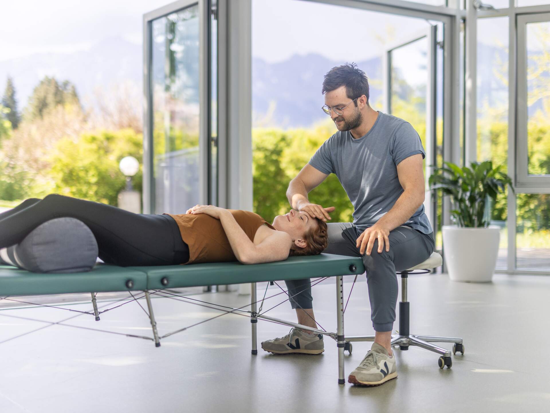 Feldenkrais Therapeut gibt einer Patientin einfühlsam Anleitung bei einer Körperübung
