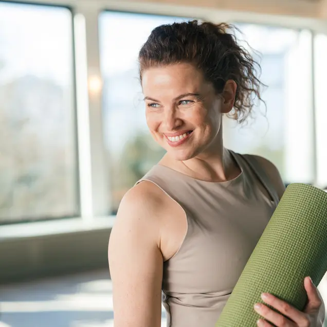 Smiling woman with yoga mat
