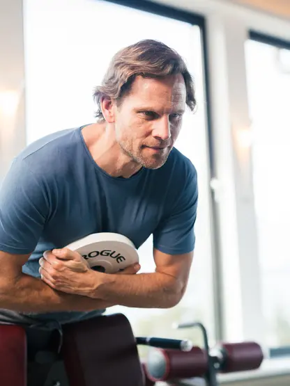 Mann trainiert Bauchmuskeln im Fitnessstudio mit Gewichtsscheibe