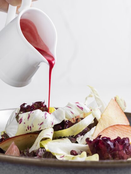 Detox-Bittersalat mit Rote-Bete-Traubendressing wird angerichtet