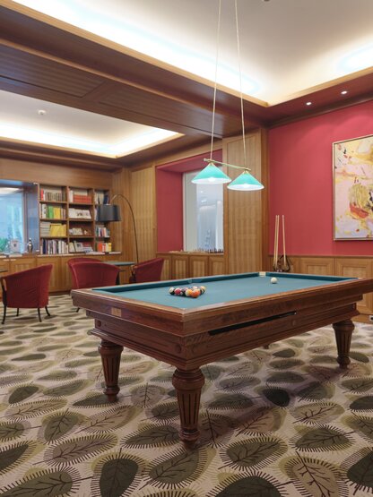 Billiard table in library with red wall and artwork