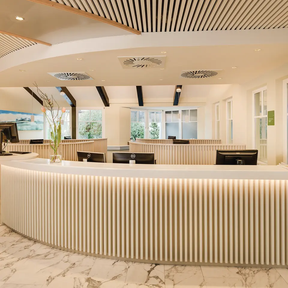 Bright, modern hotel reception with curved counter and several computers