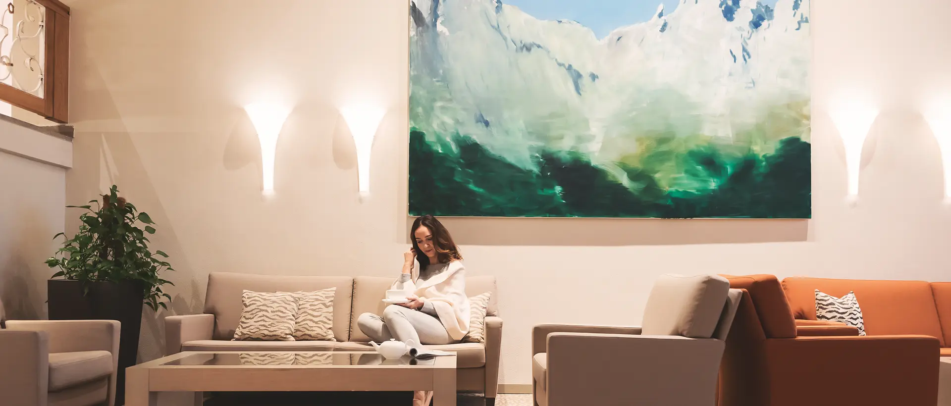 Frau sitzt auf Sofa in Lobby mit Gemälde von Bergen