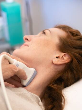 Frau bei einer Ultraschalluntersuchung der Halsschlagader in Rückenlage