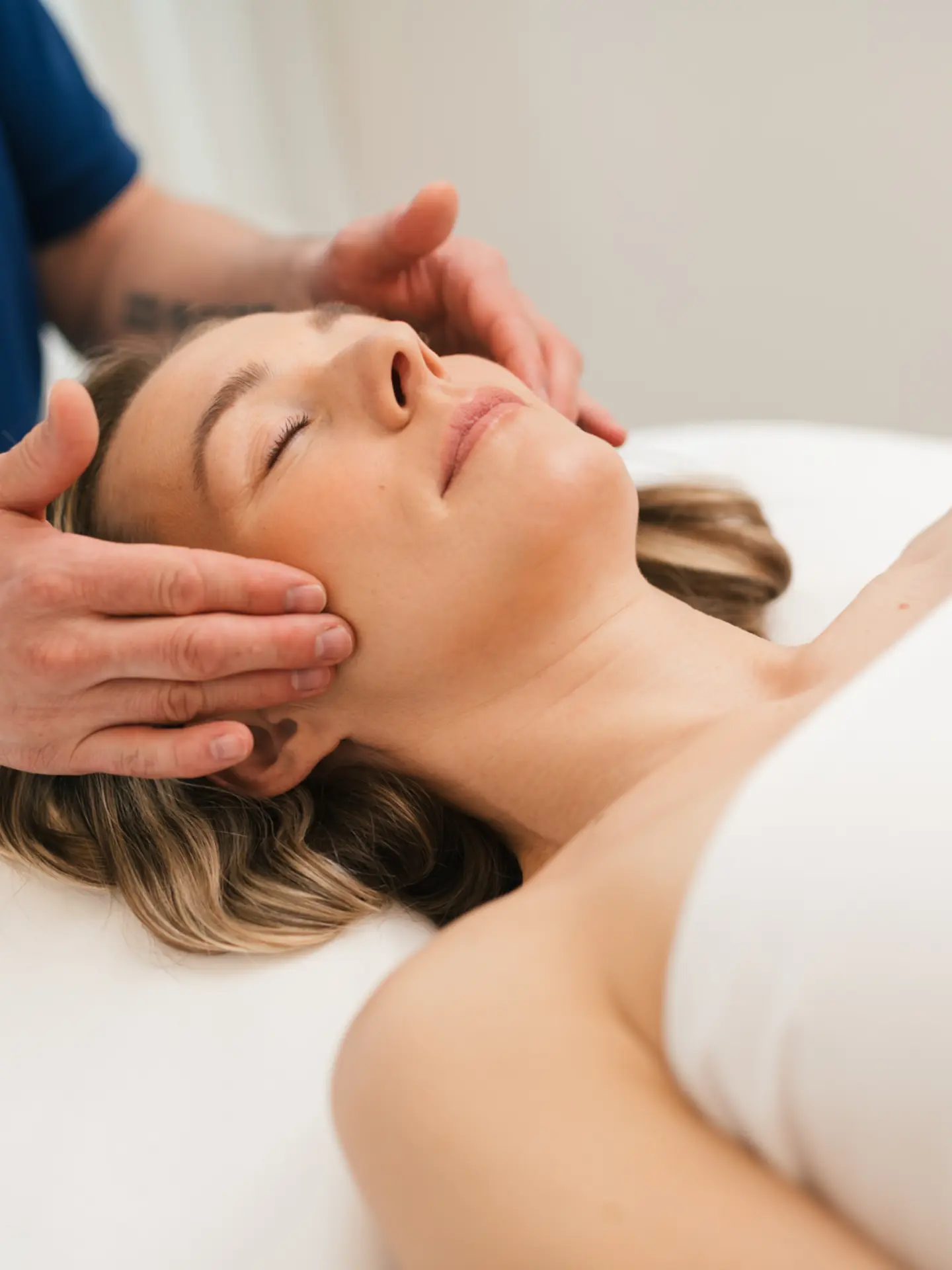 Frau erhält Gesichtsmassage von Masseur im Park Igls