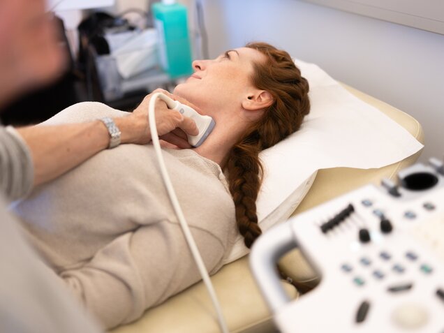 Frau bei einer Ultraschalluntersuchung der Halsschlagader in Rückenlage