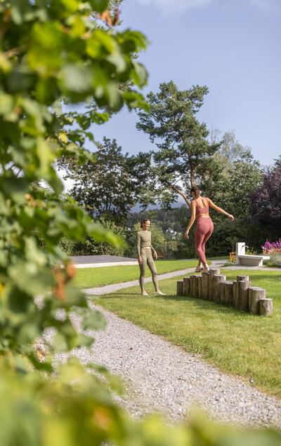 Junge Frau balanciert auf Baumstämmen im Park, Trainerin beobachtet