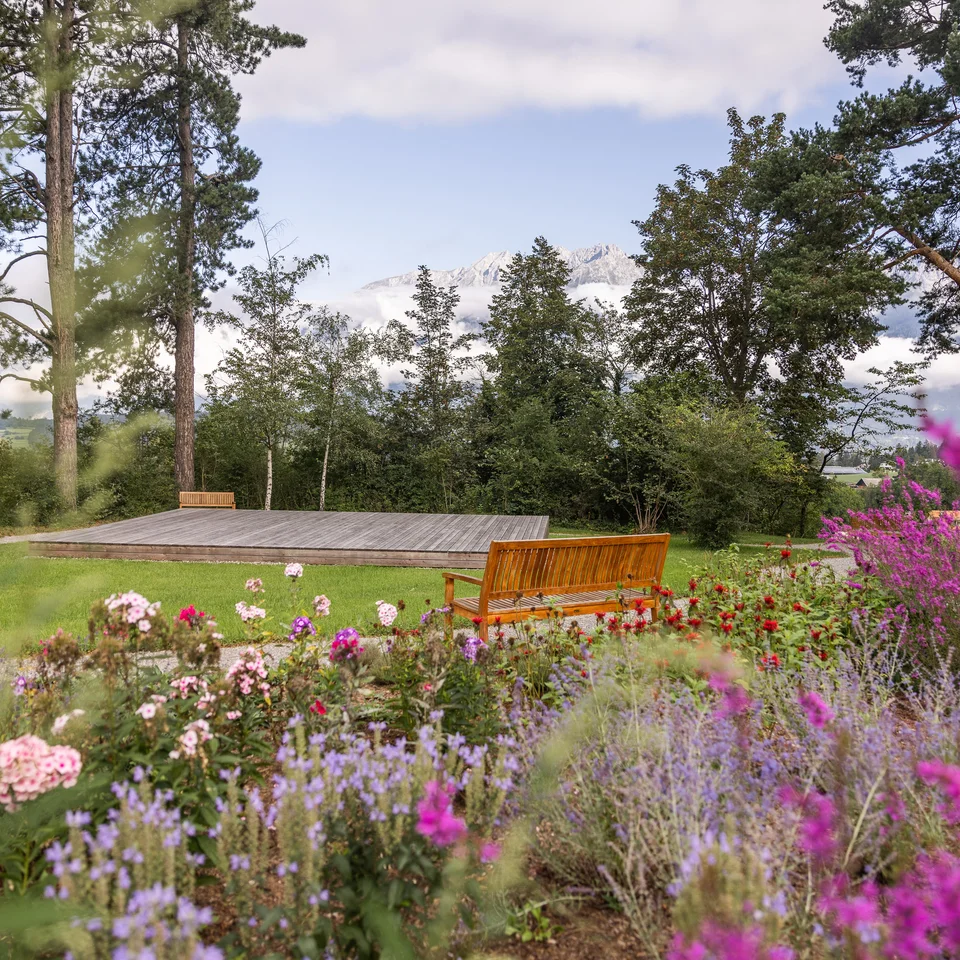 Park Igls: flowerbed, lawn with stage and bench in front of trees