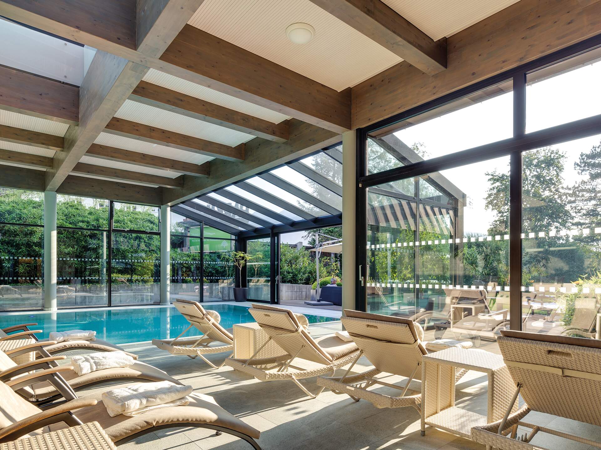 Interior view of the pool with loungers and glass roof at Park Igls