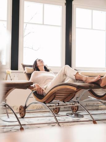 Woman relaxing on a lounger in the spa in front of a bright window