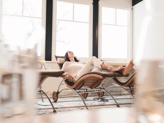 Woman relaxing on a lounger in the spa in front of a bright window