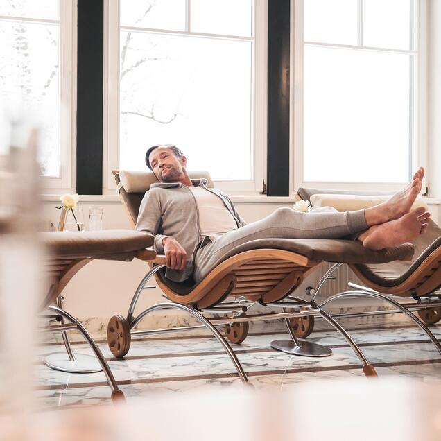 Man relaxing in lounger in spa in front of window