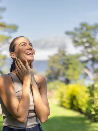 Junge Frau genießt Sonne im Garten des Park Igls