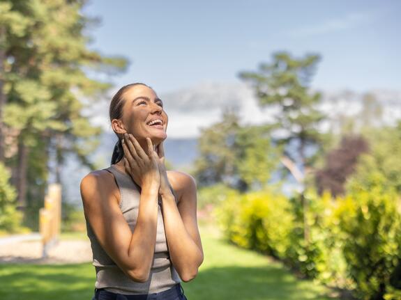 Junge Frau genießt Sonne im Garten des Park Igls