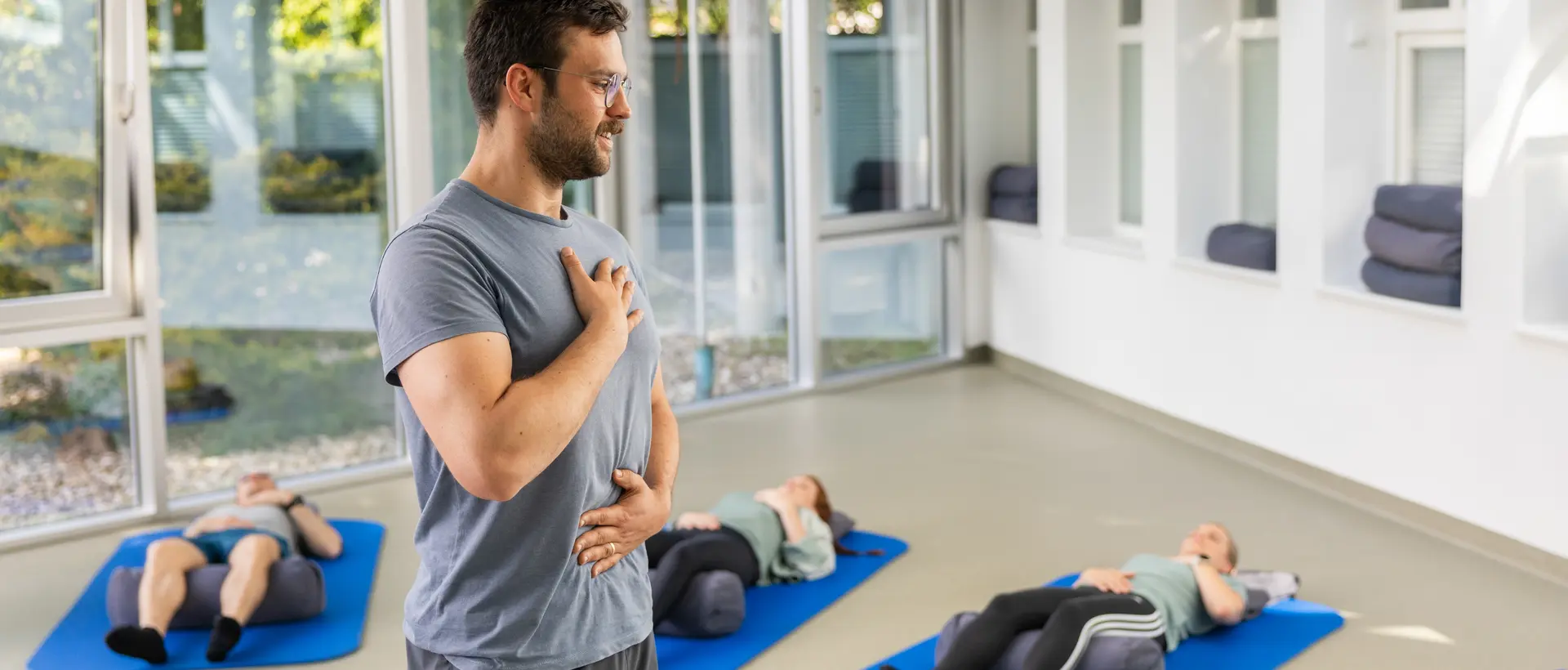 Gruppe von Menschen bei Feldenkrais-Übungen am Boden unter Anleitung eines Therapeuten