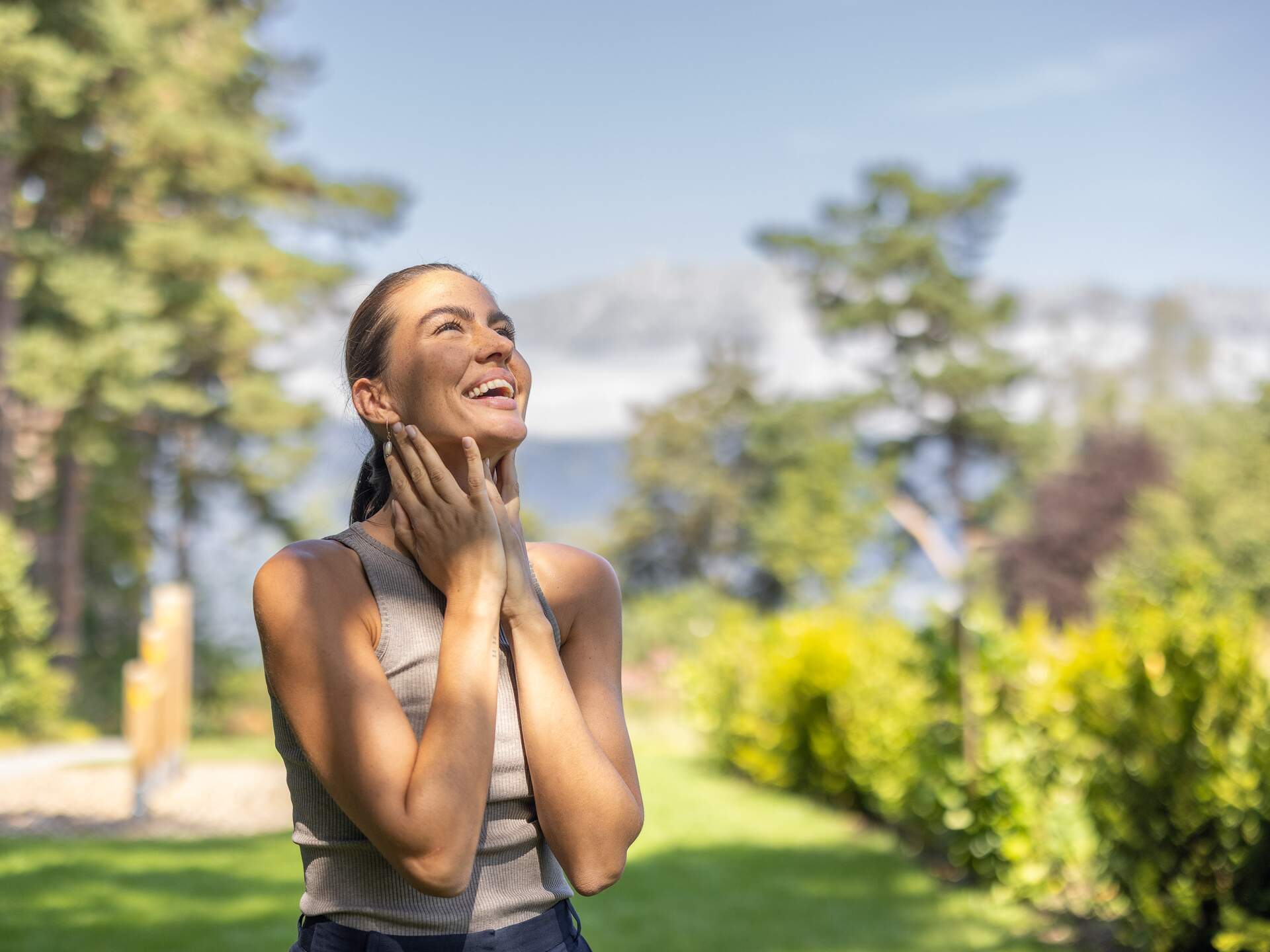 Junge Frau genießt Sonne im Garten des Park Igls