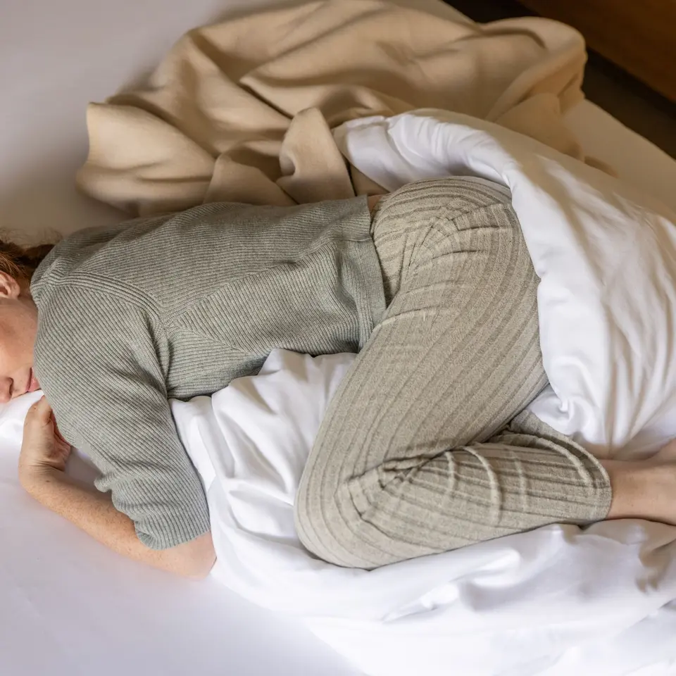 Lady cuddling in bed with duvet